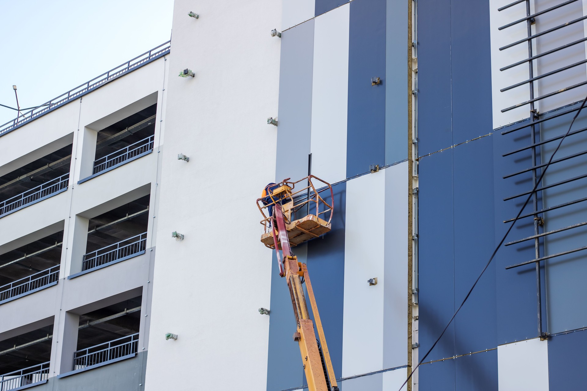 A man inside a lift is painting the side of a building